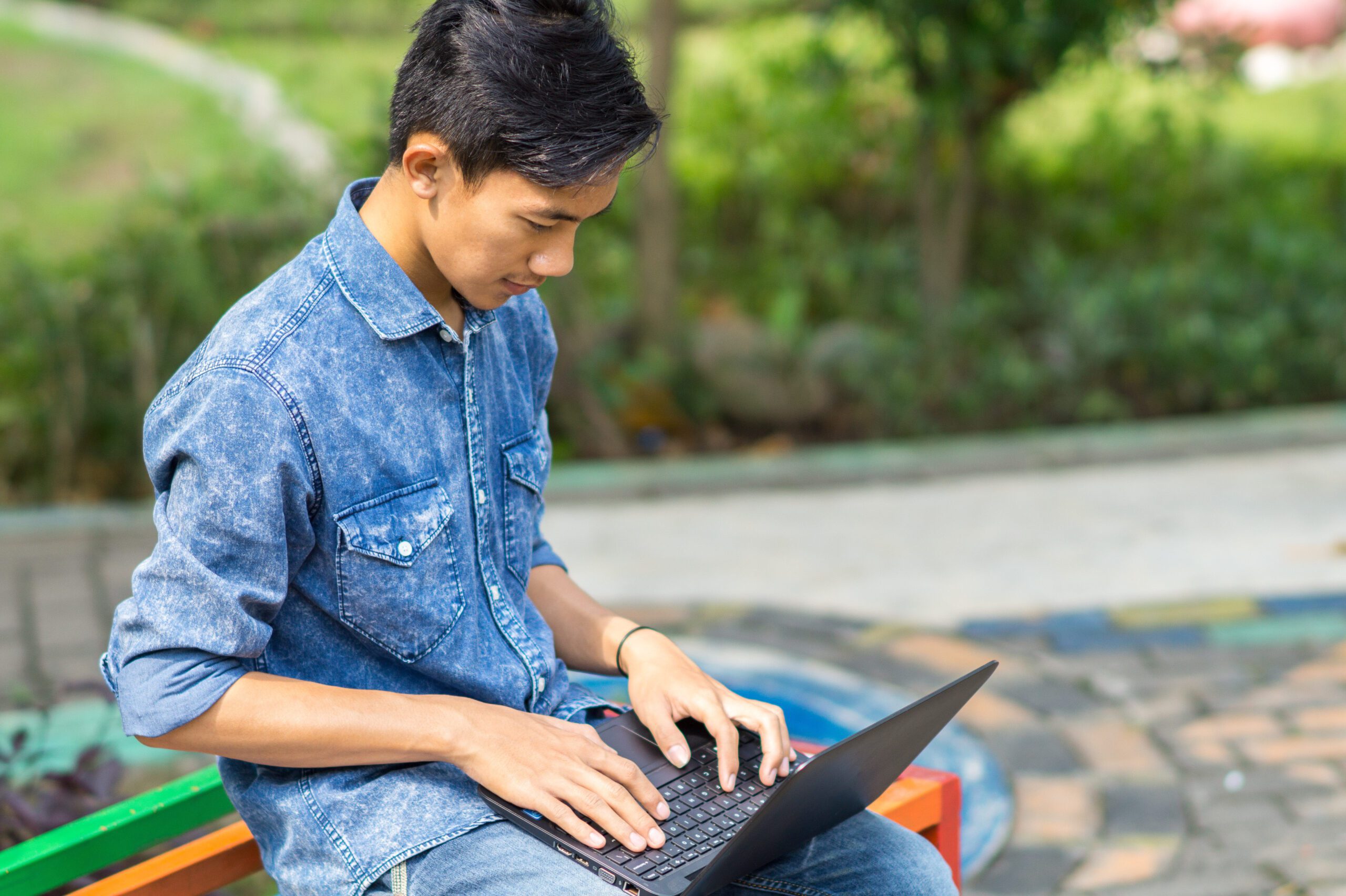 Asian young man using computer outdoor