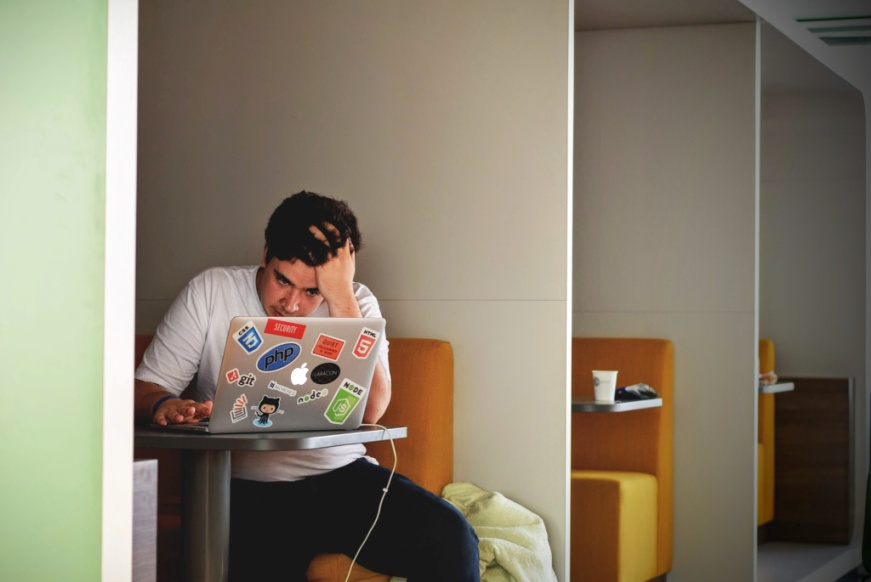 A stressed person working on a laptop.